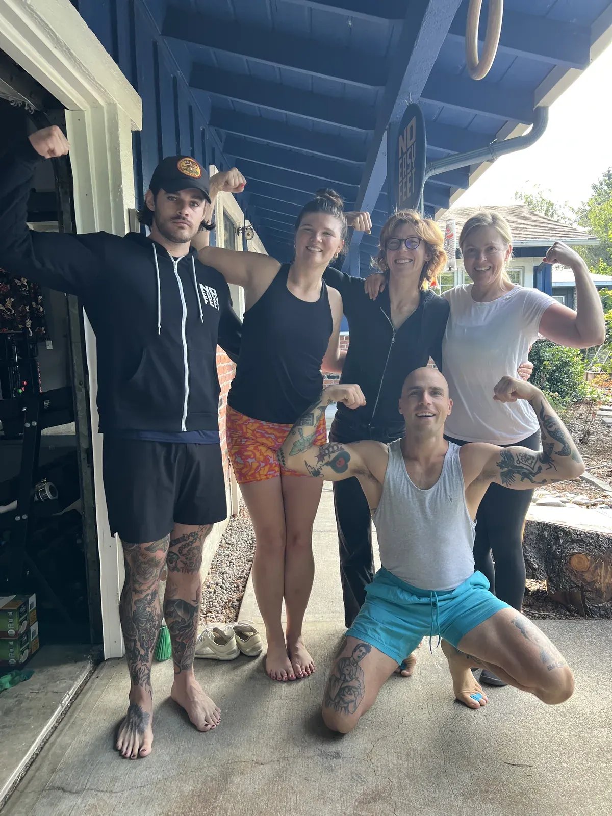 Five No Easy Feet members flexing barefoot outside the studio
