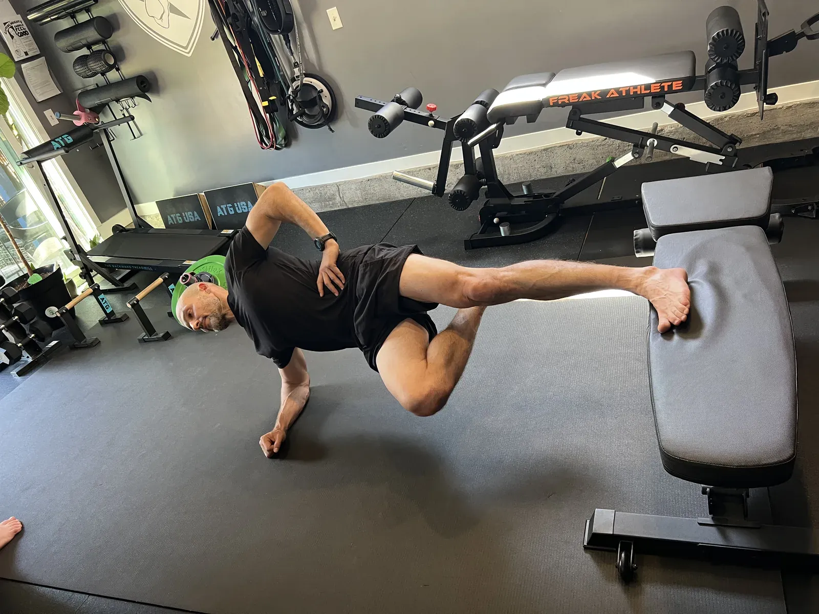 A side plank with a raised leg on a bench at the No Easy Feet gym